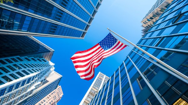 Looking up at an American flag surrounded by skyscrapers